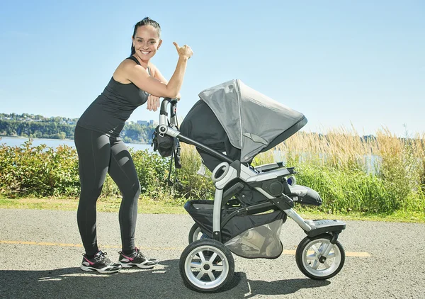 Ung mamma jogging med en baby buggy — Stockfoto