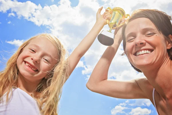 Happy mother and daughter holding a trophy high up — Stock Photo, Image