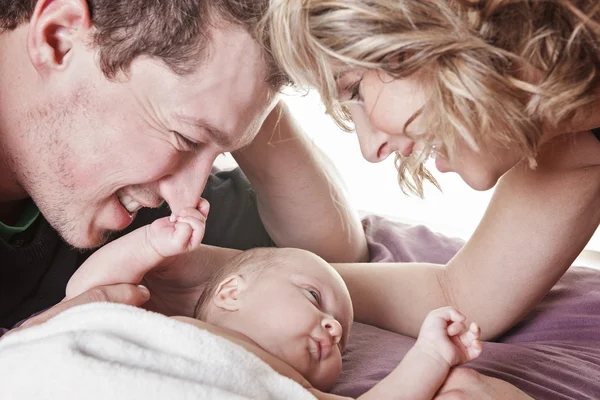 美丽的夫妇抱着婴儿在床上. — 图库照片