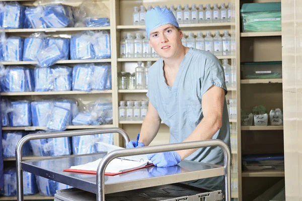 Mannen aan het werk op een steriliserende plaats in het ziekenhuis. Hij controleert de inventaris. — Stockfoto