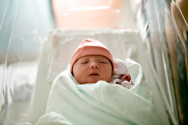 Bebé recién nacido dormido, envuelto en una manta del hospital y con un sombrero —  Fotos de Stock
