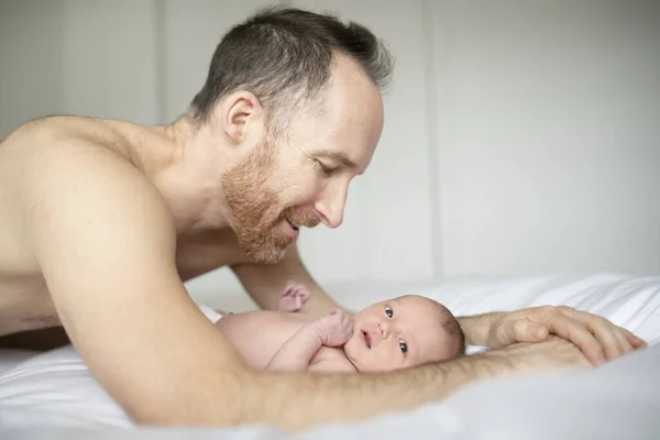 Um pai com um bebê recém-nascido na cama — Fotografia de Stock