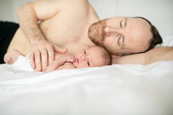 Um pai com um bebê recém-nascido na cama — Fotografia de Stock