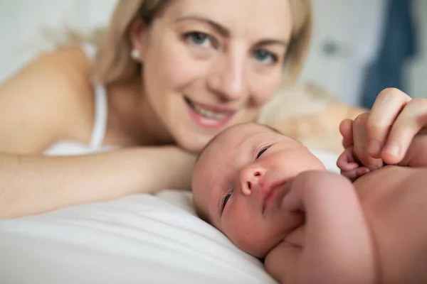 Μια γυναίκα με ένα νεογέννητο μωρό στο κρεβάτι. — Φωτογραφία Αρχείου