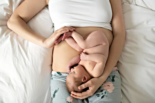 Uma mãe com um bebê recém-nascido na cama na barriga como o feto — Fotografia de Stock