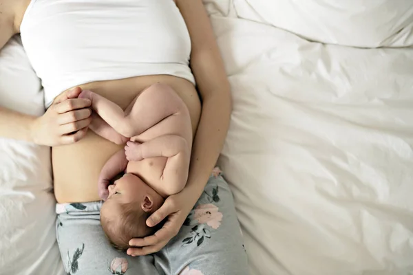 Uma mãe com um bebê recém-nascido na cama na barriga como o feto — Fotografia de Stock