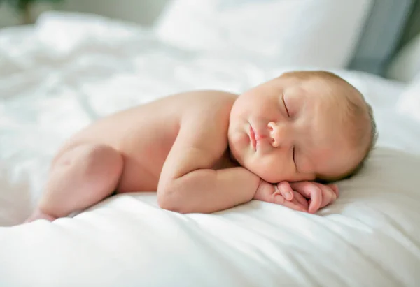 Una dulce niña recién nacida desnuda durmiendo en una cama blanca —  Fotos de Stock