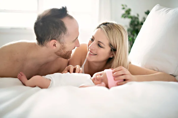 Een familie ouder met een pasgeboren baby in bed — Stockfoto