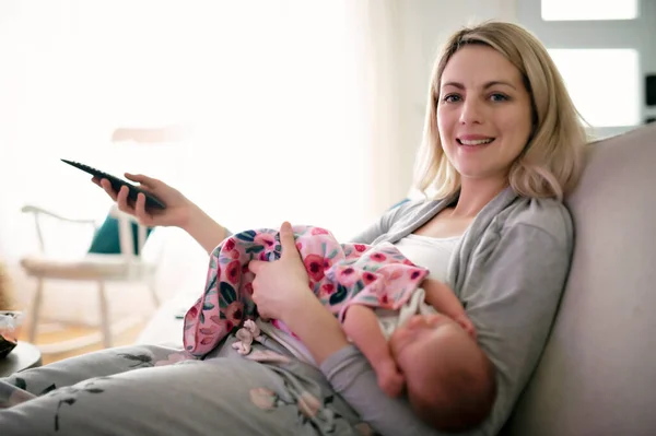 Une mère regarde la télévision avec son sommeil nouveau-né — Photo