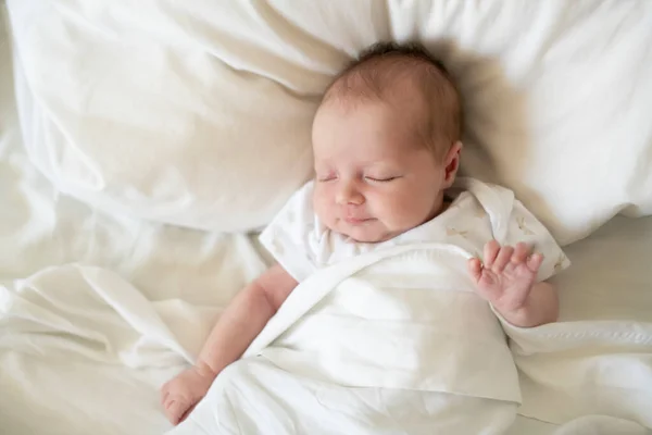 Uma doce menina recém-nascida dormindo na cama branca — Fotografia de Stock