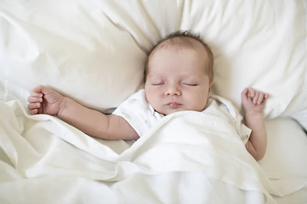 Una dulce niña recién nacida durmiendo en una cama blanca —  Fotos de Stock