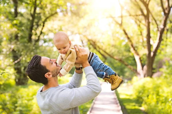 Father and baby having fun in the forest holding his baby in the air — Stock Photo, Image
