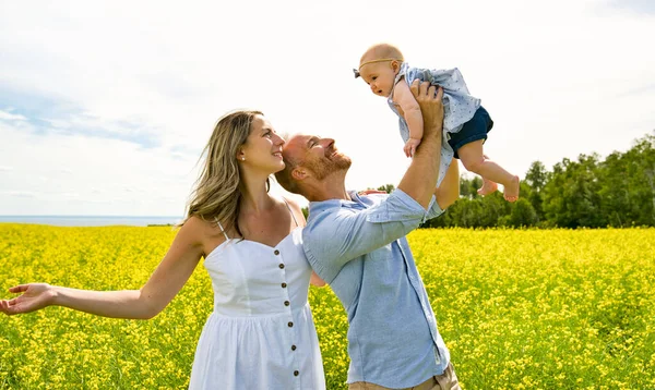 Lycklig familj med liten dotter spenderar tid tillsammans i soligt fält — Stockfoto