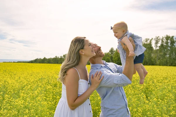 Happy family with little daughter spending time together in sunny field — Stock Photo, Image