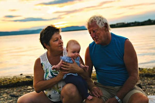 Os avós brincando com sua neta bebê na praia — Fotografia de Stock