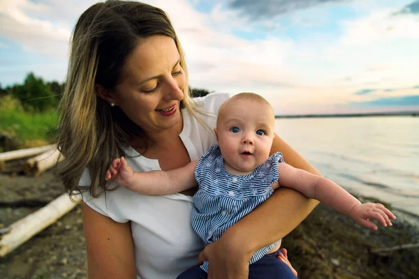 Mother and child girl at the sunset on the waterscape — Stock Photo, Image