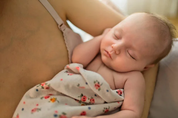 Ung mor som håller i sitt nyfödda barn sitter på en stol i vardagsrummet. Nära syn på barnet — Stockfoto