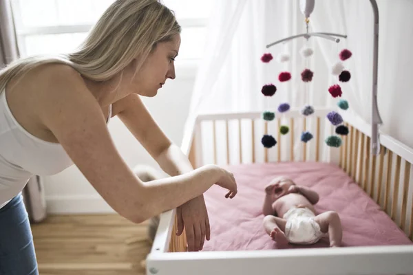 Madre que sufre de depresión postnatal cerca de cuna con lindo bebé en casa — Foto de Stock