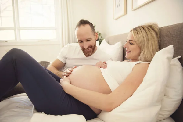 Bella donna incinta e il suo bel marito trascorrere del tempo insieme a letto — Foto Stock