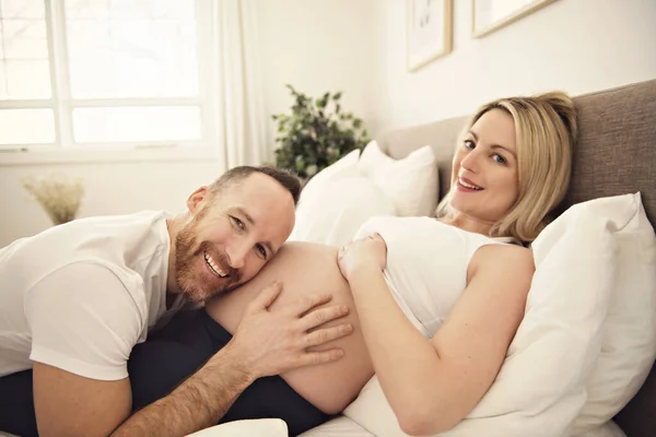 Belle femme enceinte et son beau mari passent du temps ensemble dans le ventre de l'oreille du lit — Photo