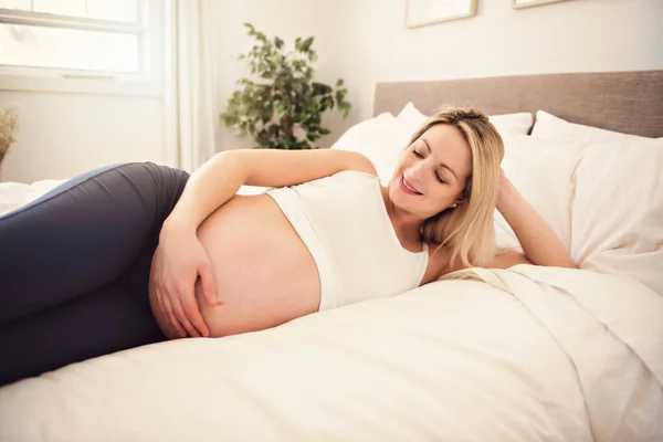 Zwanger vrouw op het bed thuis — Stockfoto