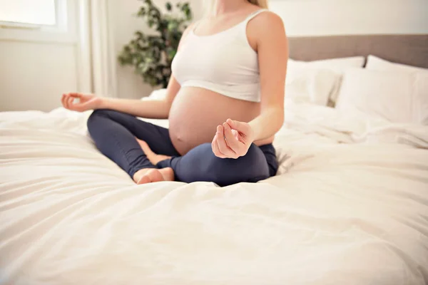 Pregnant woman doing yoga exercise on bed — Stock Photo, Image