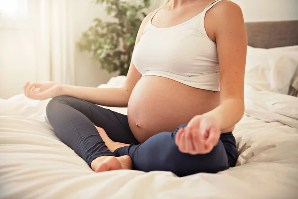 Zwangere vrouw doet yoga oefening op bed — Stockfoto