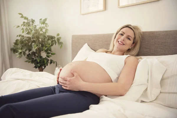 Zwanger vrouw op het bed thuis — Stockfoto