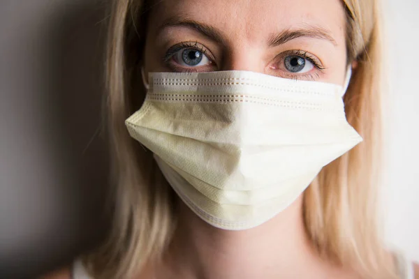 Hoofd en schouders portret van vrouwelijke arts dragen beschermende masker tegen witte achtergrond — Stockfoto