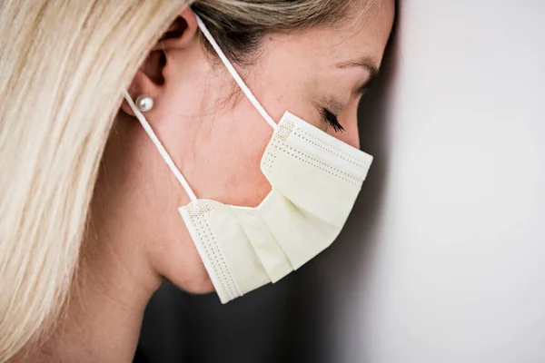 Hoofd en schouders portret van vrouwelijke arts dragen beschermende masker tegen witte achtergrond — Stockfoto