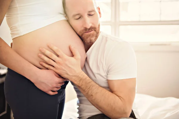 Marito nella stanza del bambino a casa con la pancia della donna incinta — Foto Stock