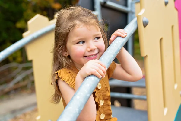 Happy Souriant enfant fille jouer à aire de jeux en plein air dans un beau parc — Photo