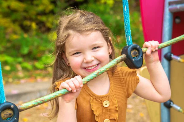 Šťastné usmívající se dítě dívka hrát na hřišti venku v pěkném parku — Stock fotografie