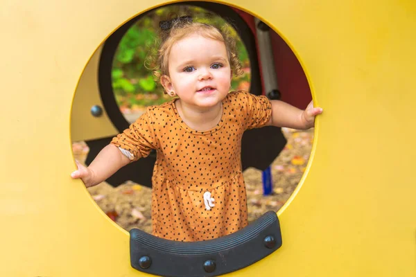 Glad leende barn flicka leka på lekplatsen utomhus i en trevlig park — Stockfoto