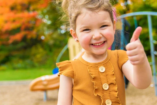 Sorrindo feliz menina brincando no playground ao ar livre em um parque agradável — Fotografia de Stock