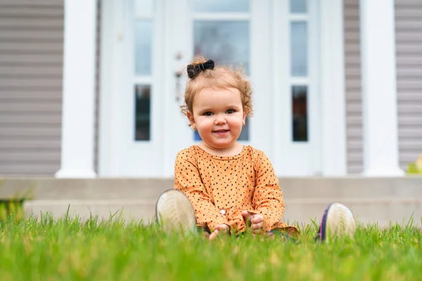 Criança bonita e agradável sentar na frente da casa da família — Fotografia de Stock
