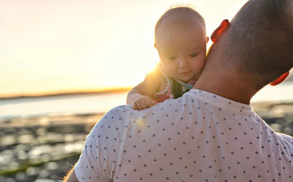 Father and baby child girl at the sunset on the waterscape view from back — Stock Photo, Image