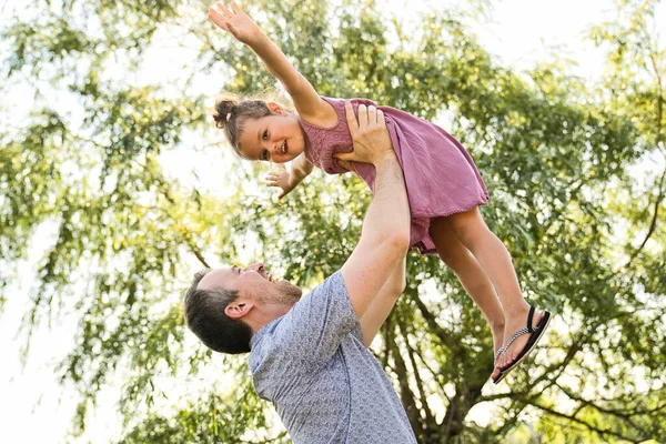 Père avec une petite fille debout à l'extérieur par l'arbre. — Photo
