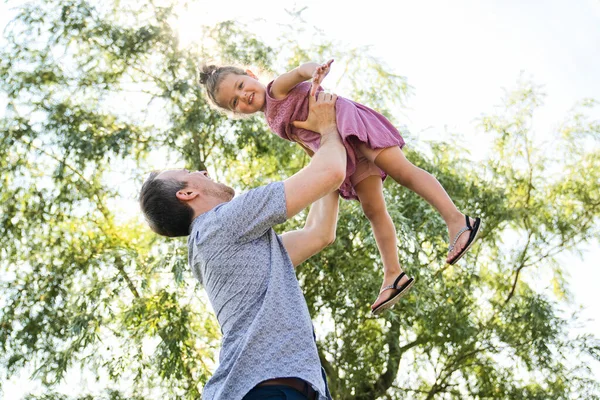 Father with small daughter standing outdoors by tree. — Stock Photo, Image