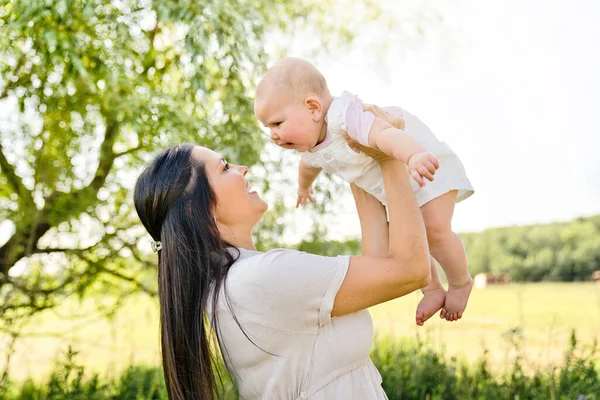 Una madre con una niña de pie al aire libre — Foto de Stock