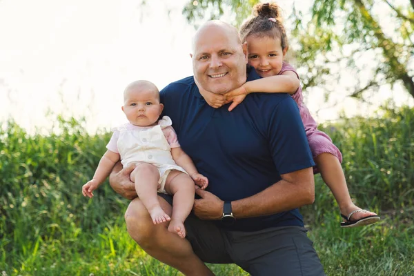 Grandfather spending time with little baby girl and littledaughter during the day — Stock Photo, Image