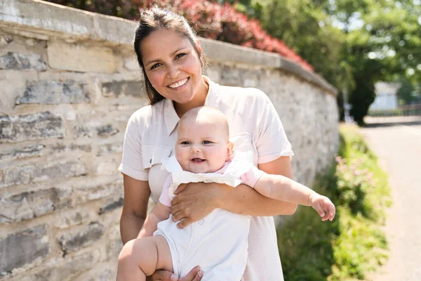 En mor med baby pige stående udendørs - Stock-foto