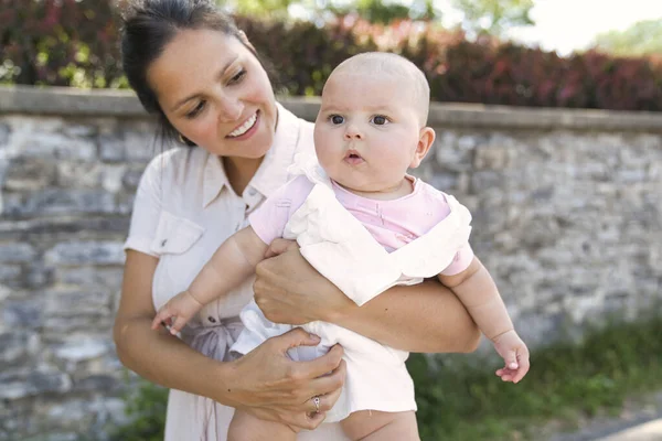 En mor med baby pige stående udendørs - Stock-foto