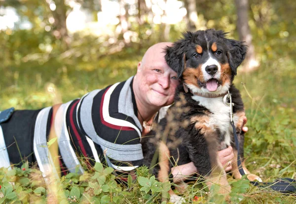 Bernese Mountain Dog cachorro con su dueño de pie en el parque forestal — Foto de Stock