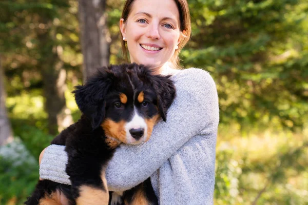 Cachorrinho Bernese Mountain Dog com seu dono de pé no parque florestal — Fotografia de Stock