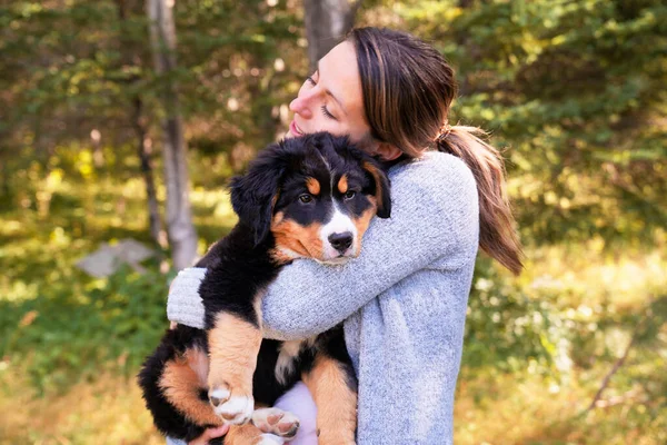 Bernese Mountain Dog puppy with his owner standing in forest park — Stock Photo, Image