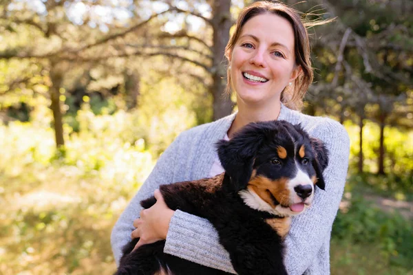 Bernese Mountain Dog cachorro con su dueño de pie en el parque forestal — Foto de Stock