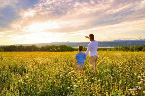 Happy family of father and child on field at the sunset having fun pointing something — Stock Photo, Image
