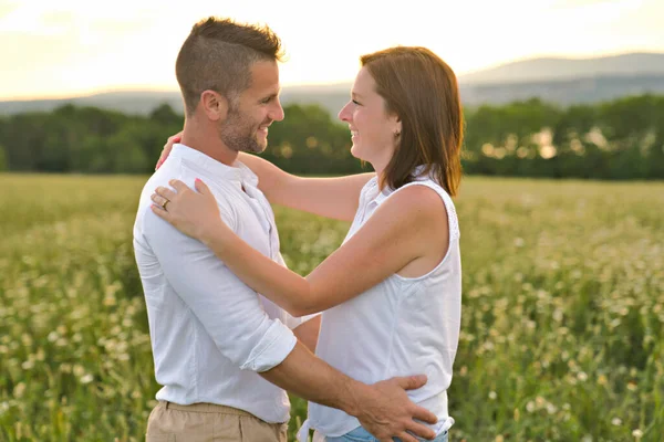 Junges Paar küsst sich vor dem Hintergrund eines Sonnenuntergangs auf dem Feld — Stockfoto