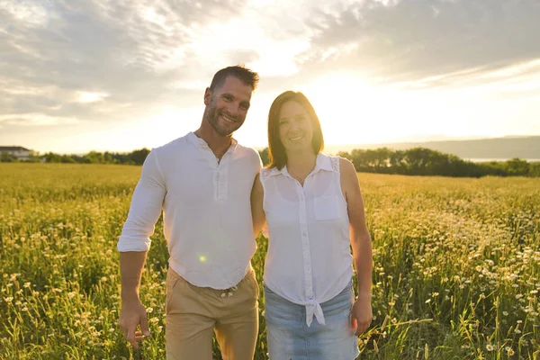 Young couple kissing on the background of a sunset in the field — Stock Photo, Image